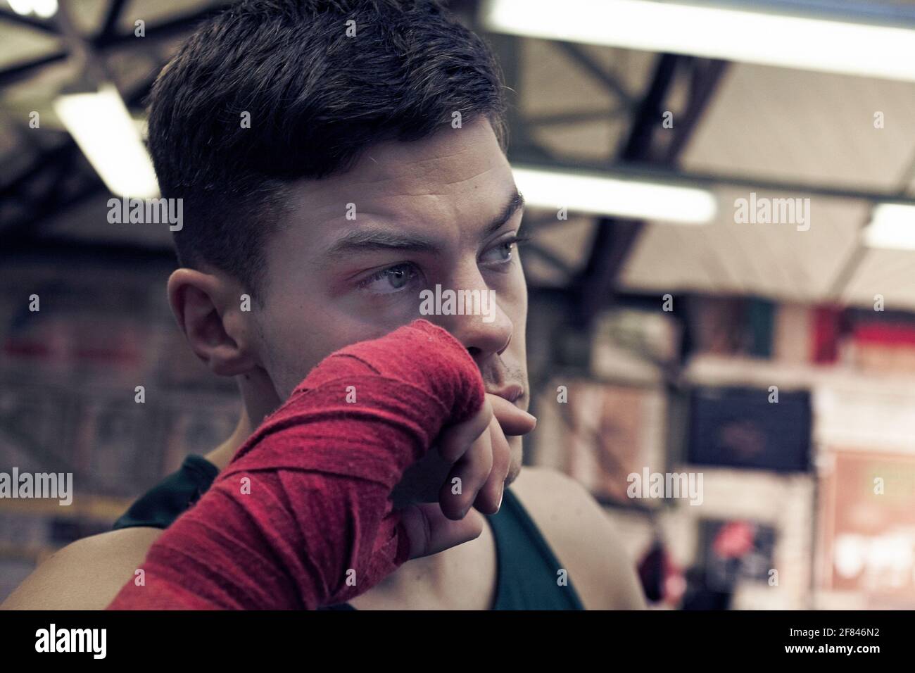 Young boxer with red hand wraps preparing for boxing practice in boxing club Stock Photo