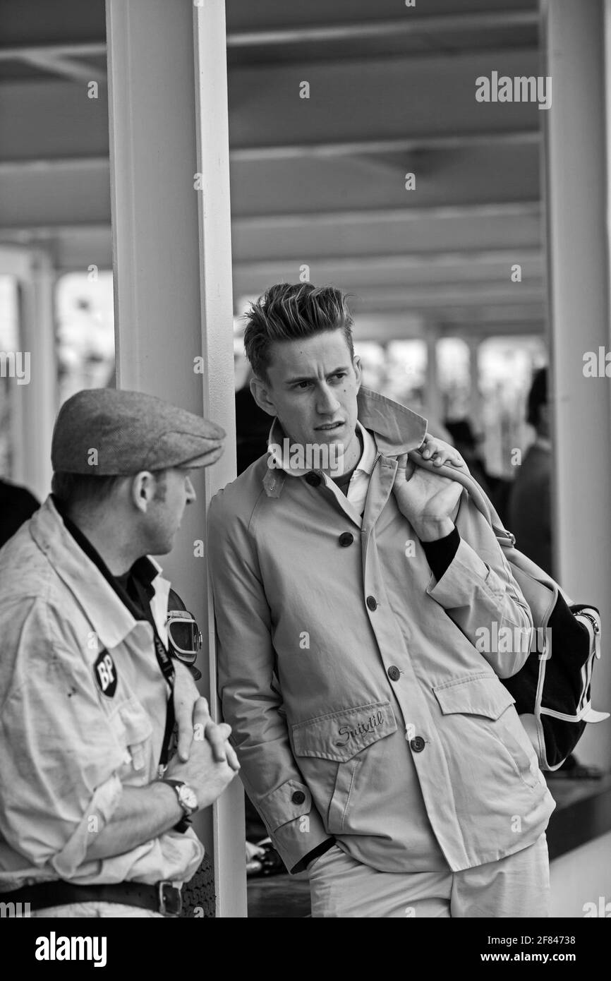 Young stylish race driver talking to pit stop mechanic during race at Goodwood Revival , UK Stock Photo