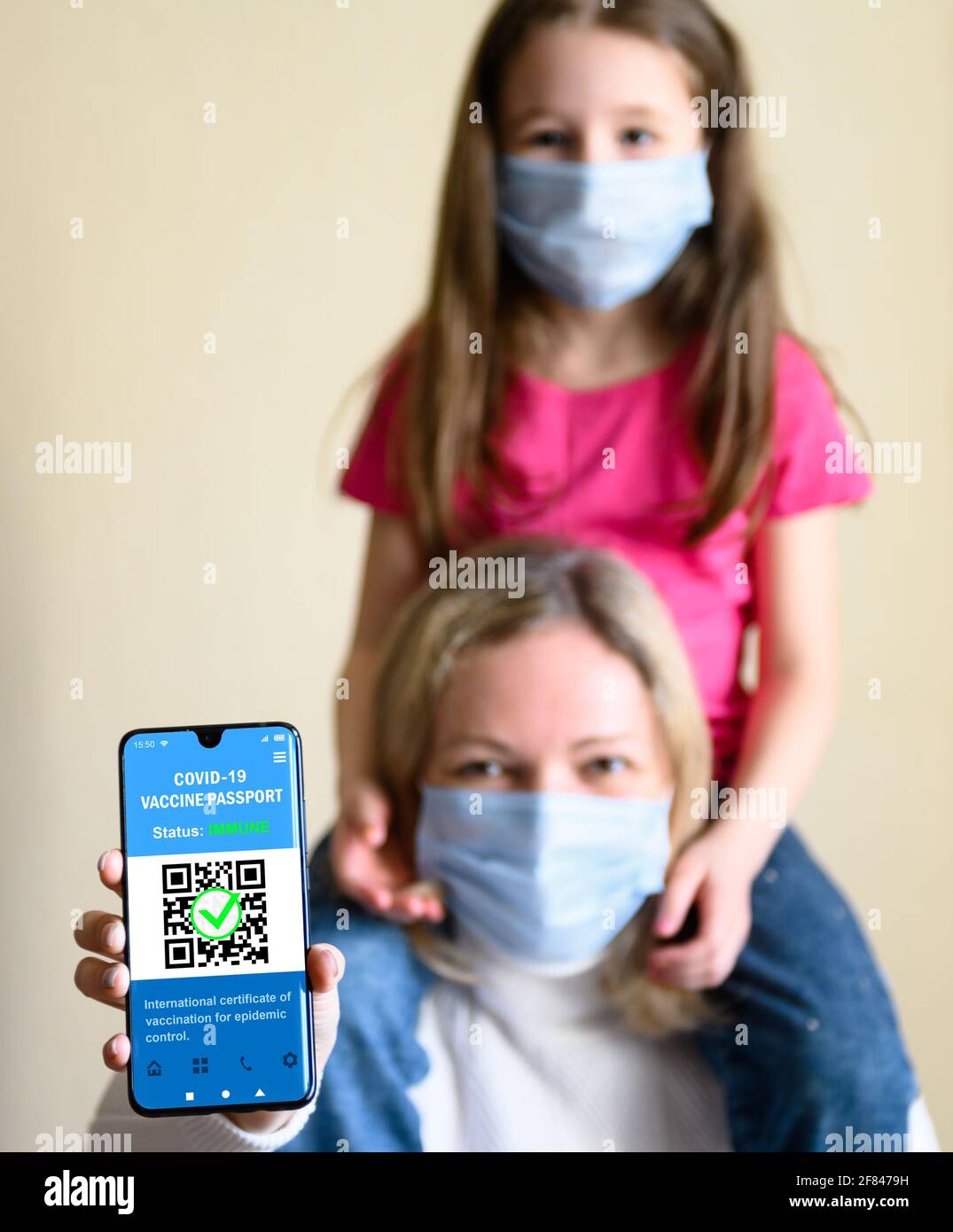 COVID-19 vaccination passport in mobile phone, happy woman with kid holds smartphone with health certificate app, digital coronavirus pass. Concept of Stock Photo