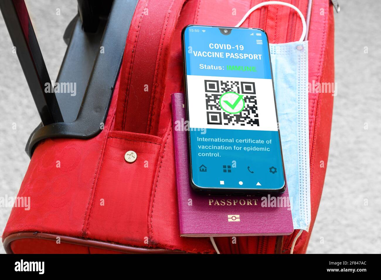 Health passport of COVID-19 vaccination in mobile phone for travel, smartphone with passport app on suitcase. Digital certificate as proof of coronavi Stock Photo