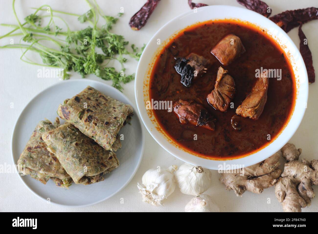 Indian flat bread made of whole wheat flour with grounded flax seed and fresh coriander leaves served with red gravy fish curry . Locally known as cor Stock Photo