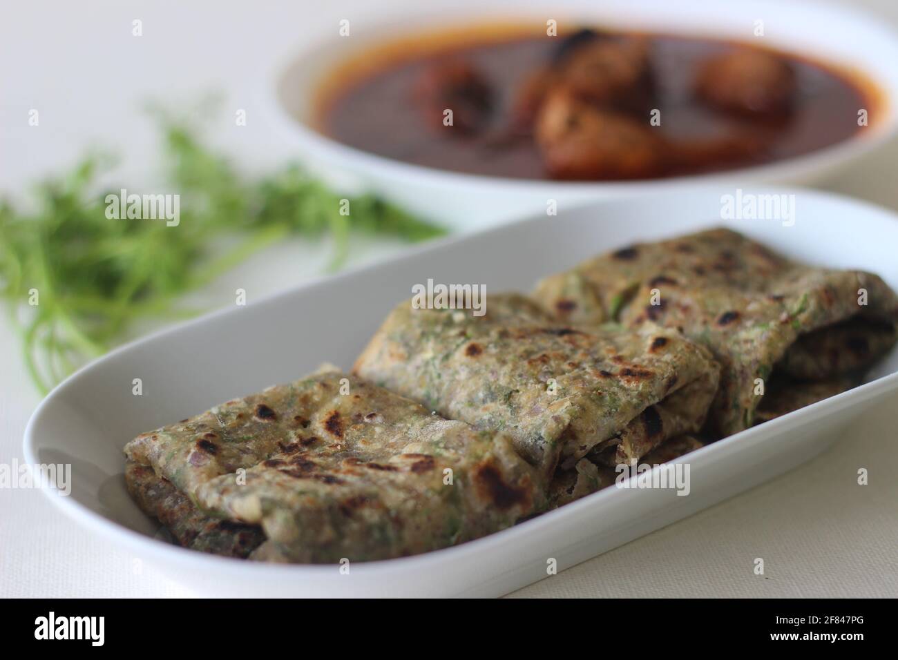 Indian flat bread made of whole wheat flour with grounded flax seed and fresh coriander leaves served with red gravy fish curry. Locally known as cori Stock Photo