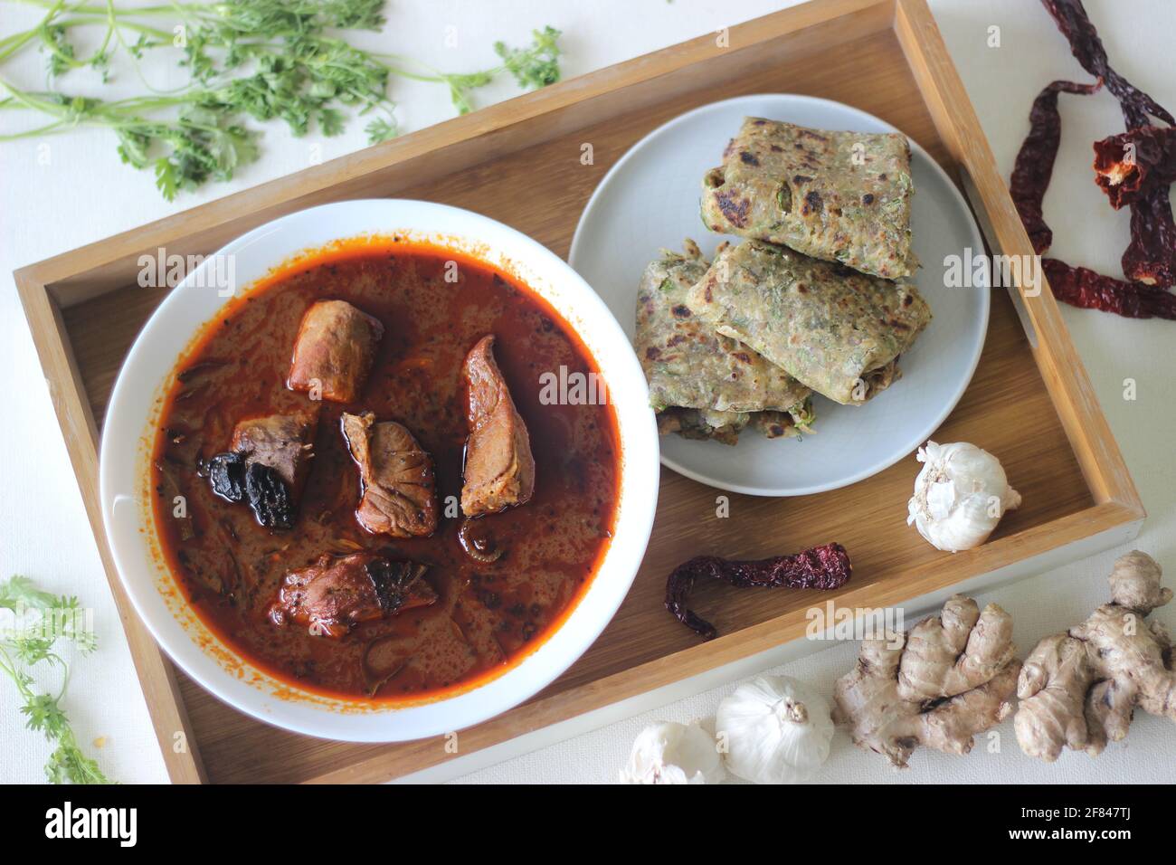 Indian flat bread made of whole wheat flour with grounded flax seed and fresh coriander leaves served with red gravy fish curry. Locally known as cori Stock Photo