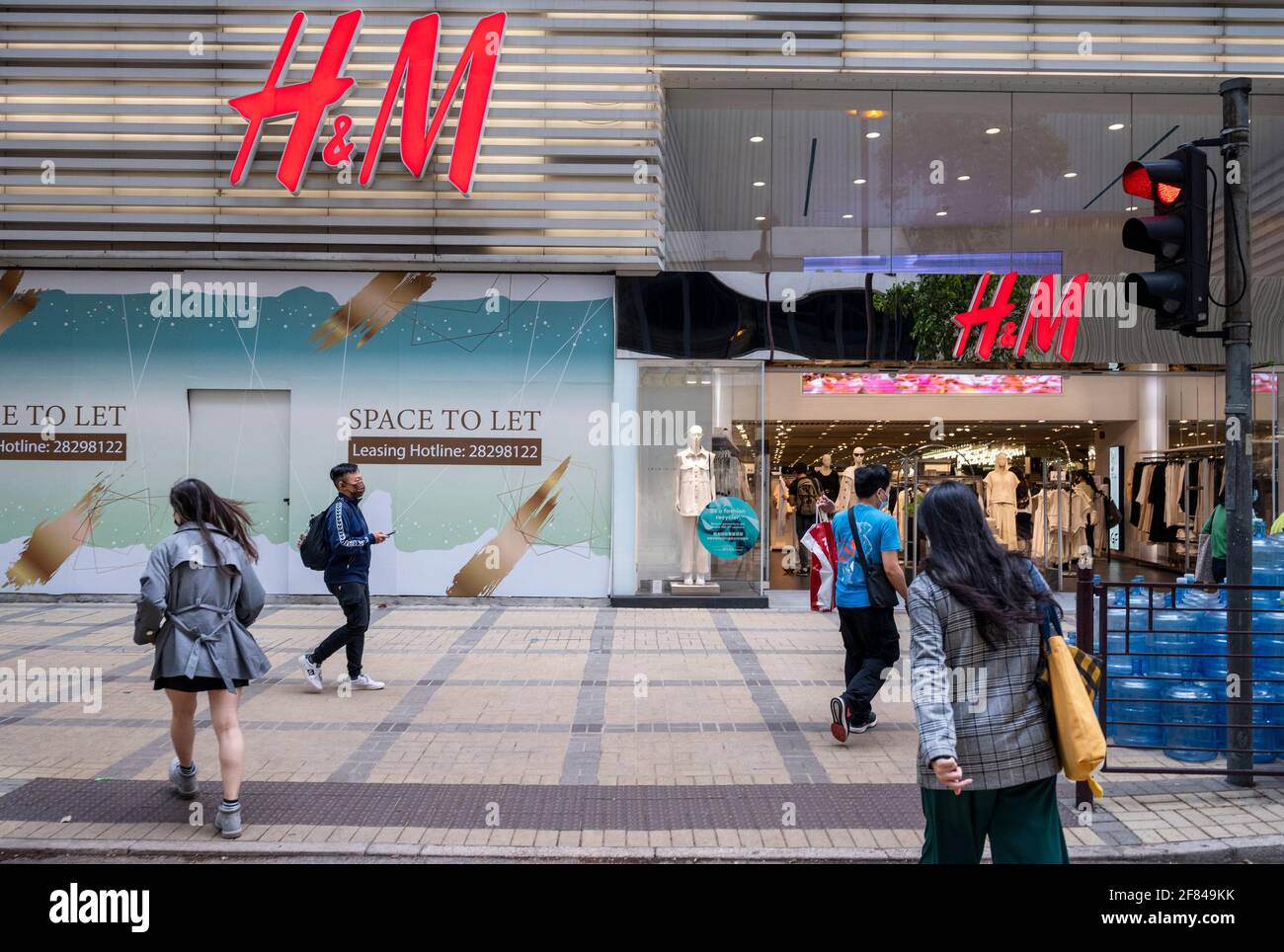 People walk past an H&M clothing store in Hong Kong, Saturday, March 27,  2021. H&M disappeared from the internet in China as the government raised  pressure on shoe and clothing brands and