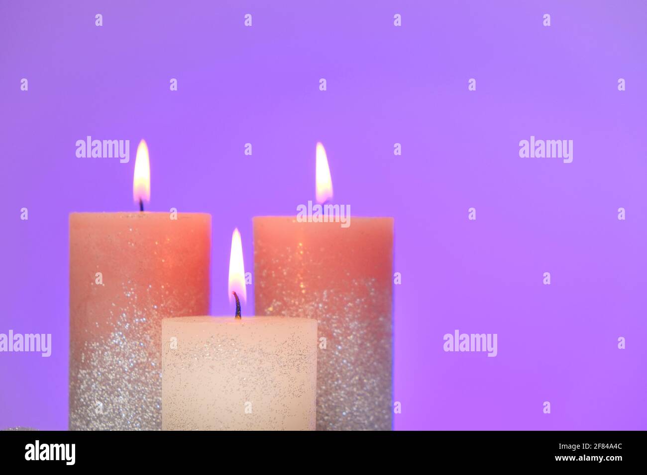 Candles set. Festive glitter candles on a purple background. Candle flame. Copy Space Stock Photo