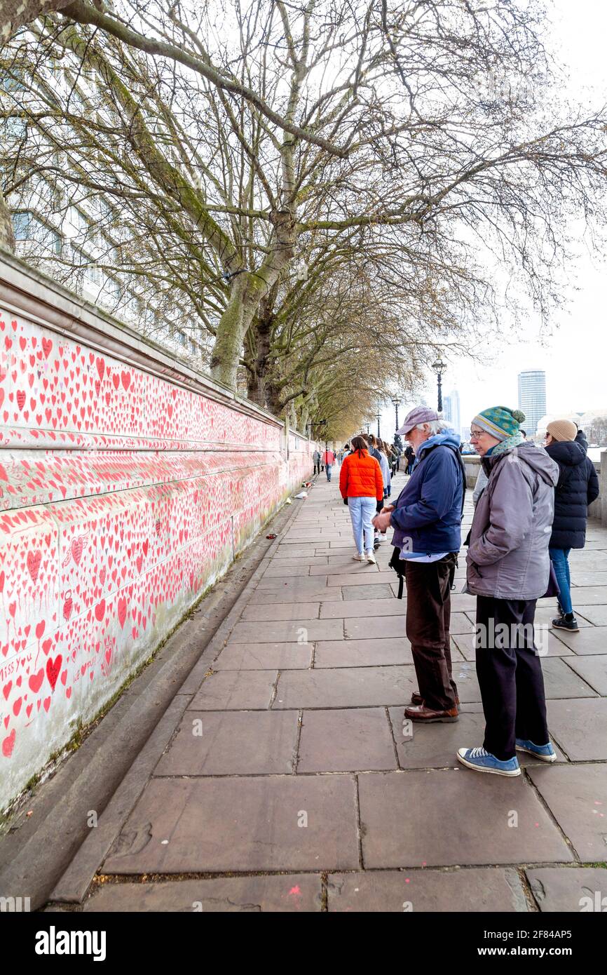11 April 2021, London, UK - Elderly couple looking at The National COVID Memorial Wall on the South Bank with hearts drawn to remember and commemorate those who lost their lives in the coronavirus pandemic Stock Photo
