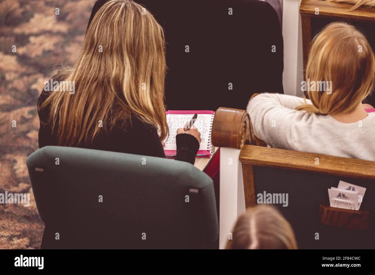 A female making notes during a lecture in a hall Stock Photo