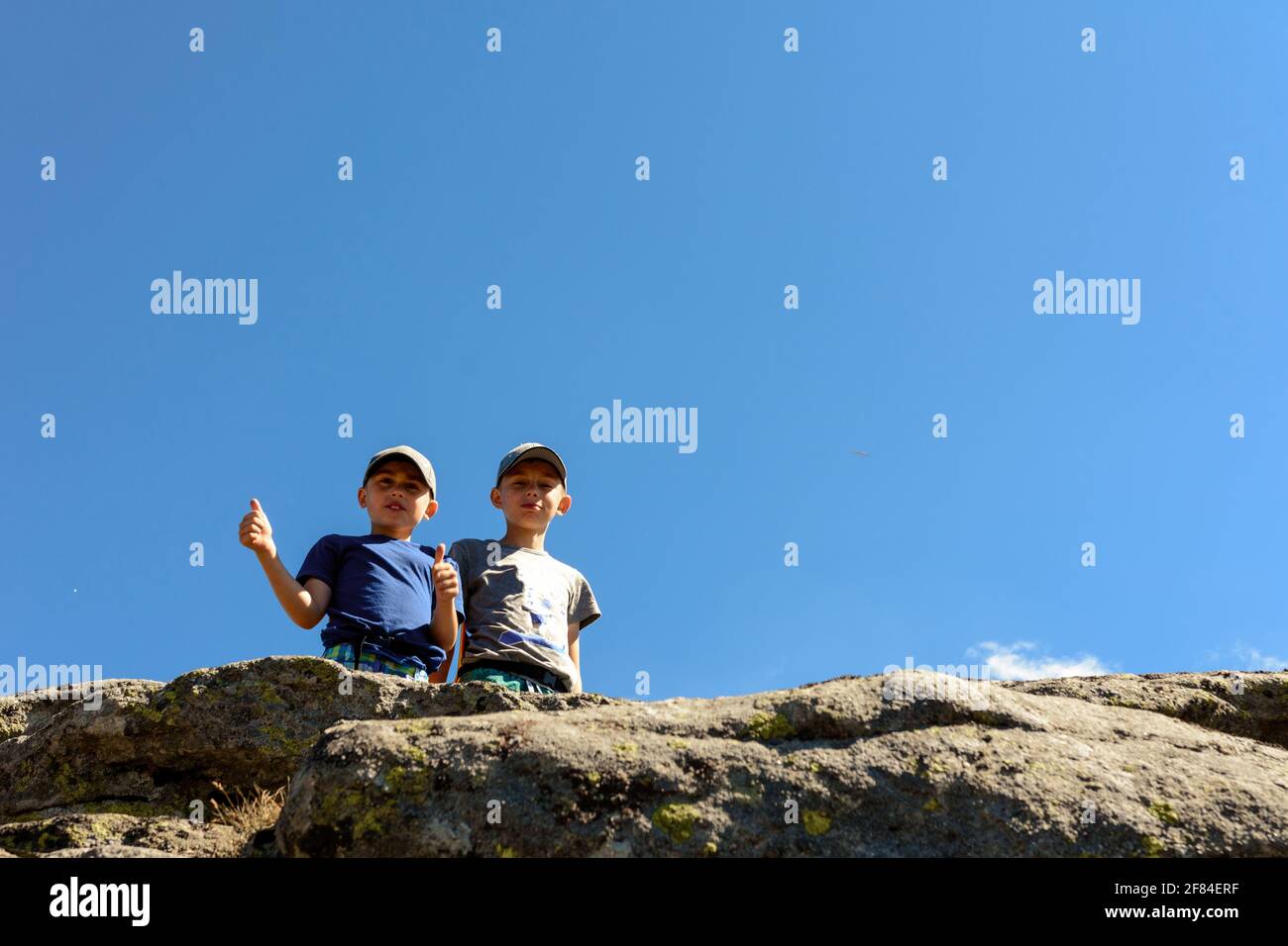 Two small children, brothers boys standing on one rocky peak, a ...