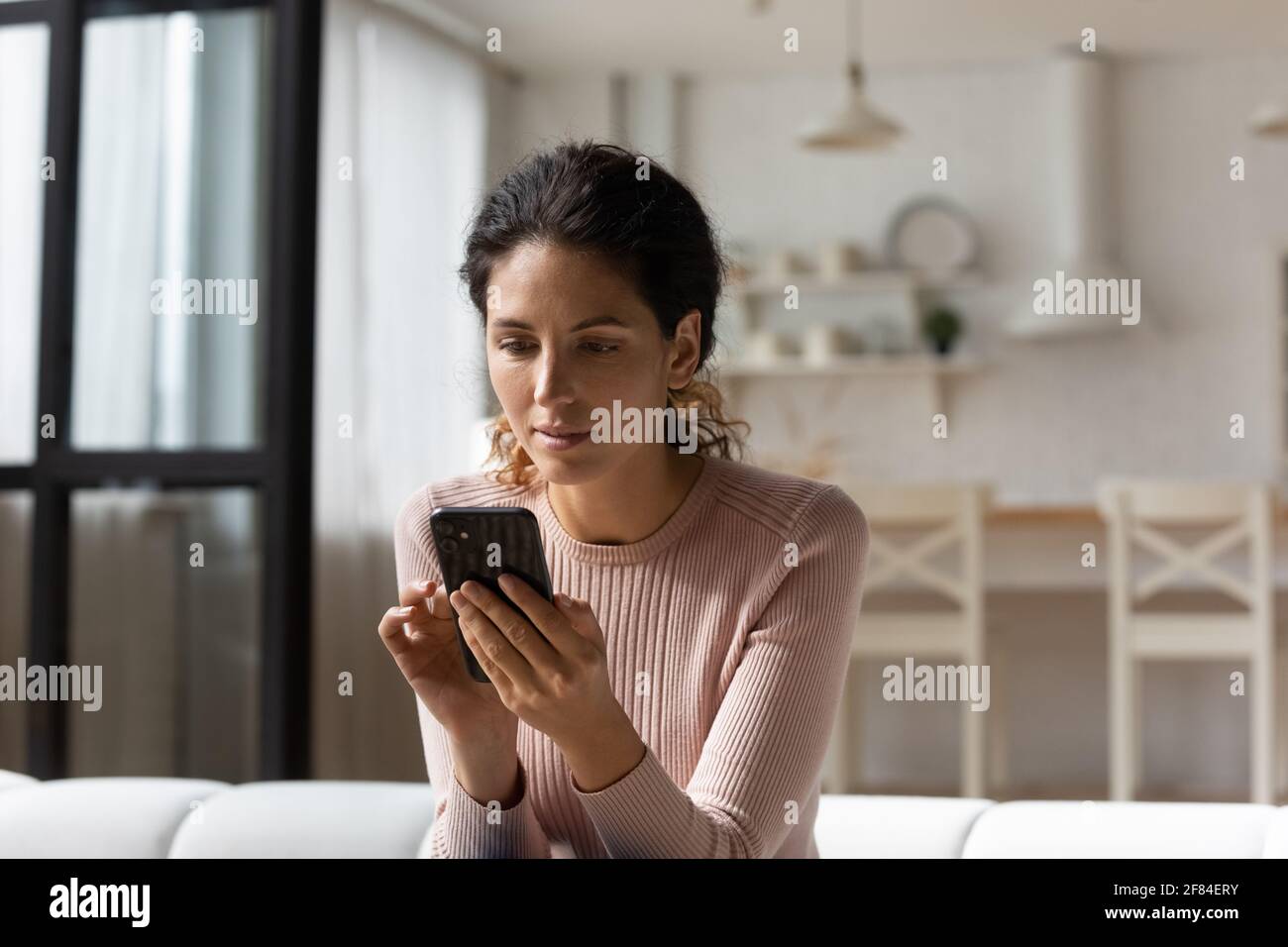 Thoughtful latin woman look at cell screen ponder on proposition Stock Photo