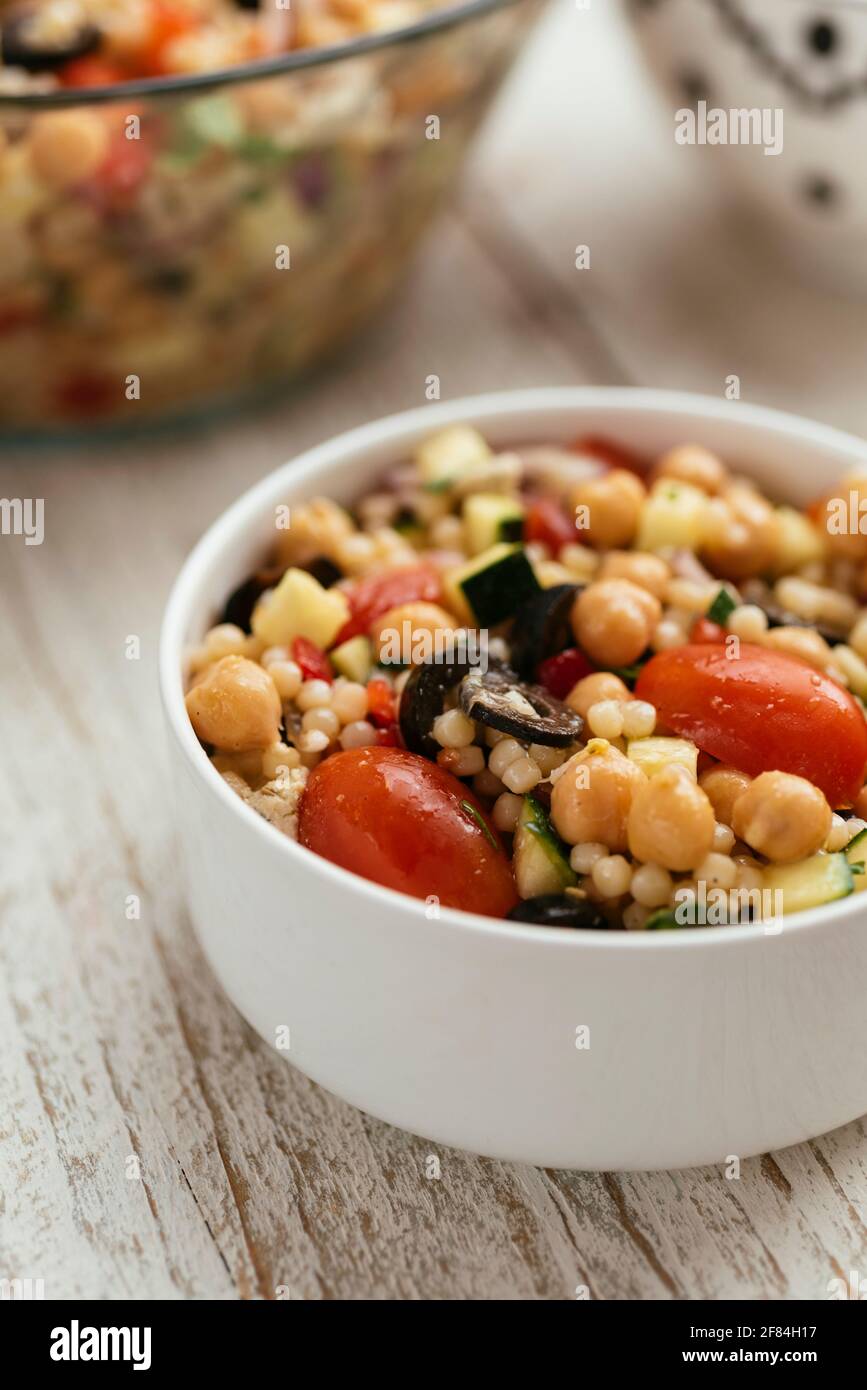 Home made Mediterranean couscous salad with bell pepper, zucchini, tomatoes, chickpeas, olive and vegan feta. Stock Photo