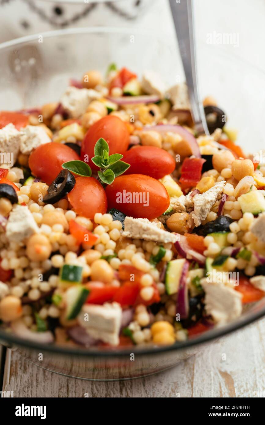 Home made Mediterranean couscous salad with bell pepper, zucchini, tomatoes, chickpeas, olive and vegan feta. Stock Photo