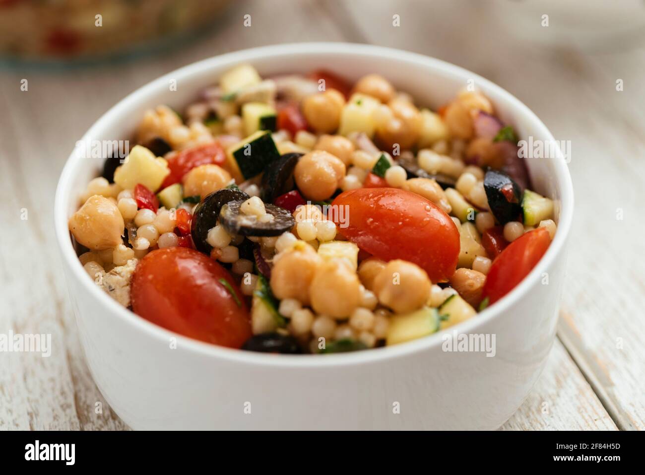 Home made Mediterranean couscous salad with bell pepper, zucchini, tomatoes, chickpeas, olive and vegan feta. Stock Photo