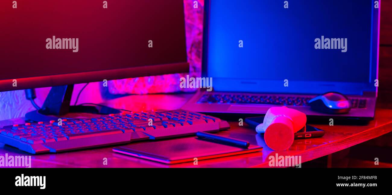 Digital design concept with a robot. Creative designer workplace in neon light. Digital tablet for drawing and an artificial arm with a pen. Distant w Stock Photo