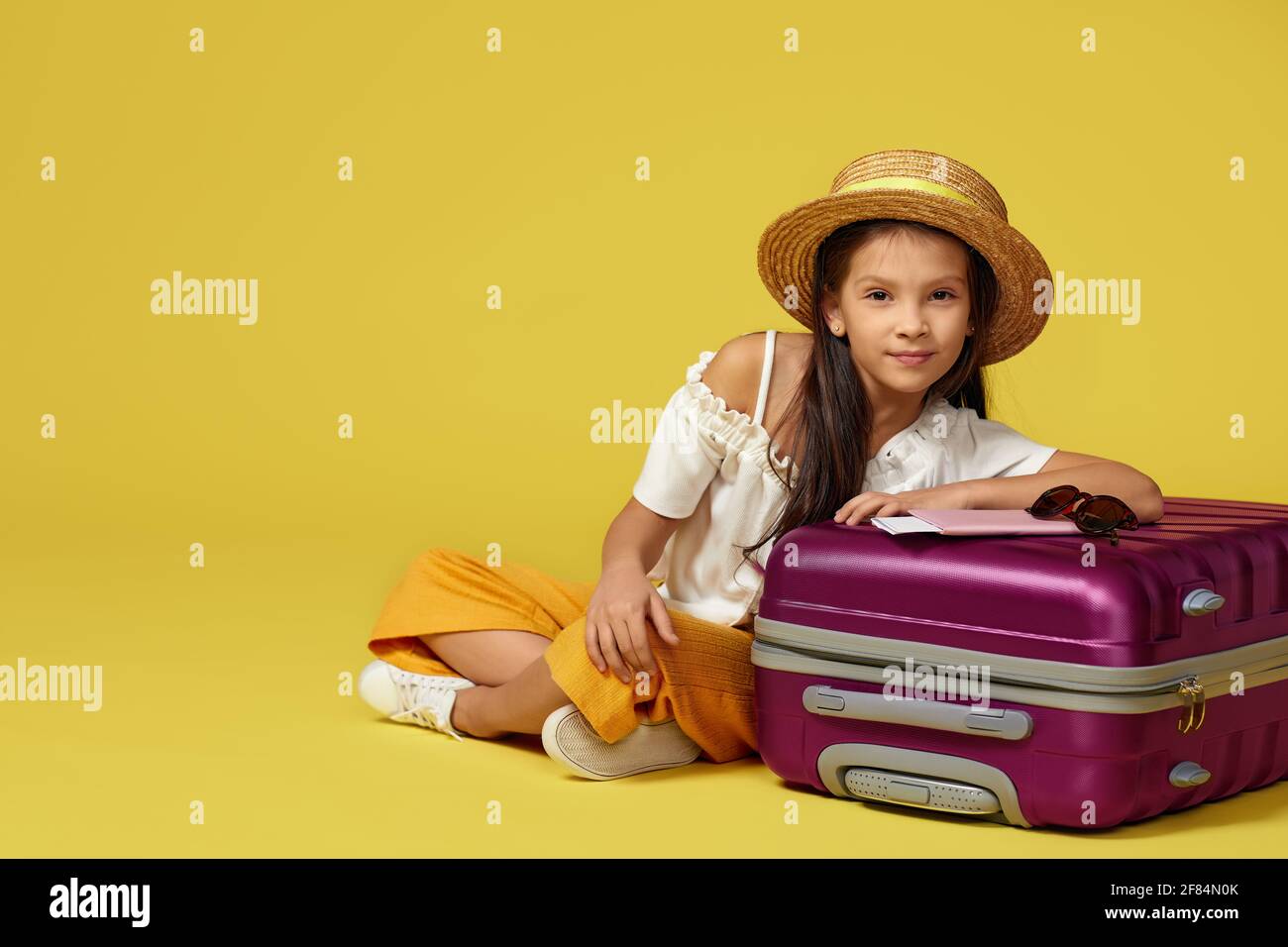 little girl with suitcase and passport sitting on floor Stock Photo