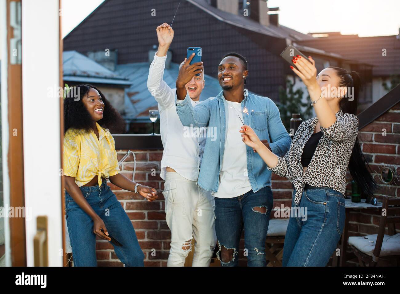 Cheerful young people in stylish clothes using smartphones and