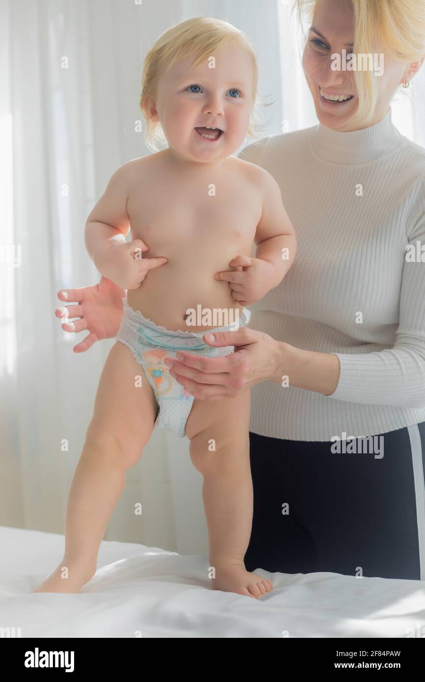 Mom holds the baby on the massage table. Happy mom and baby laugh. Stock Photo
