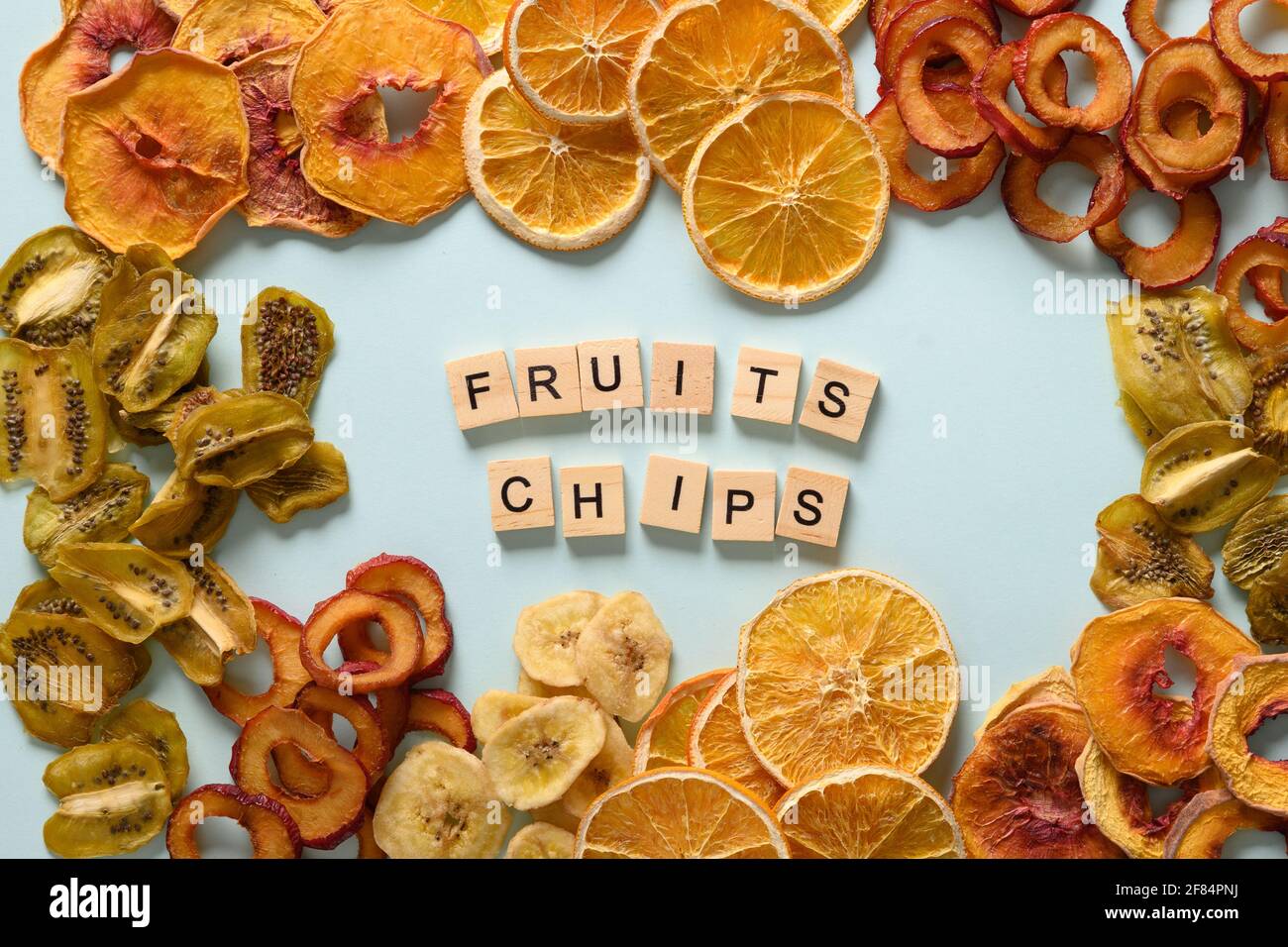 Dried sliced plums, kiwi, peach fruits chips on blue background and