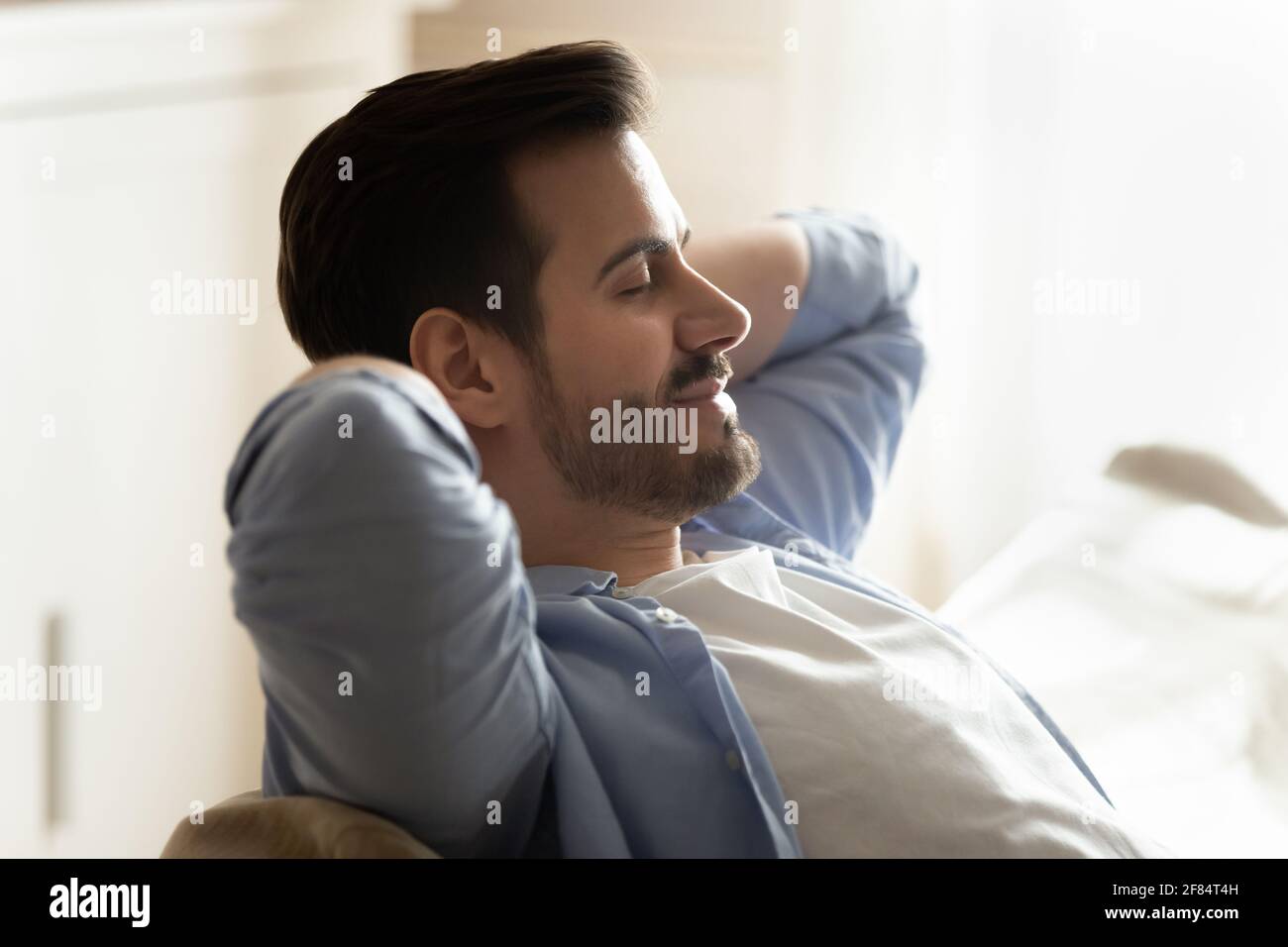Calm young man relax on sofa relieve negative emotion Stock Photo
