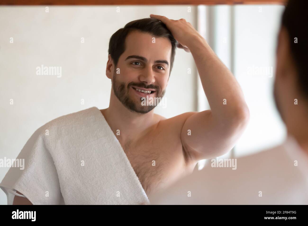 Smiling man look in mirror in bath style hair Stock Photo