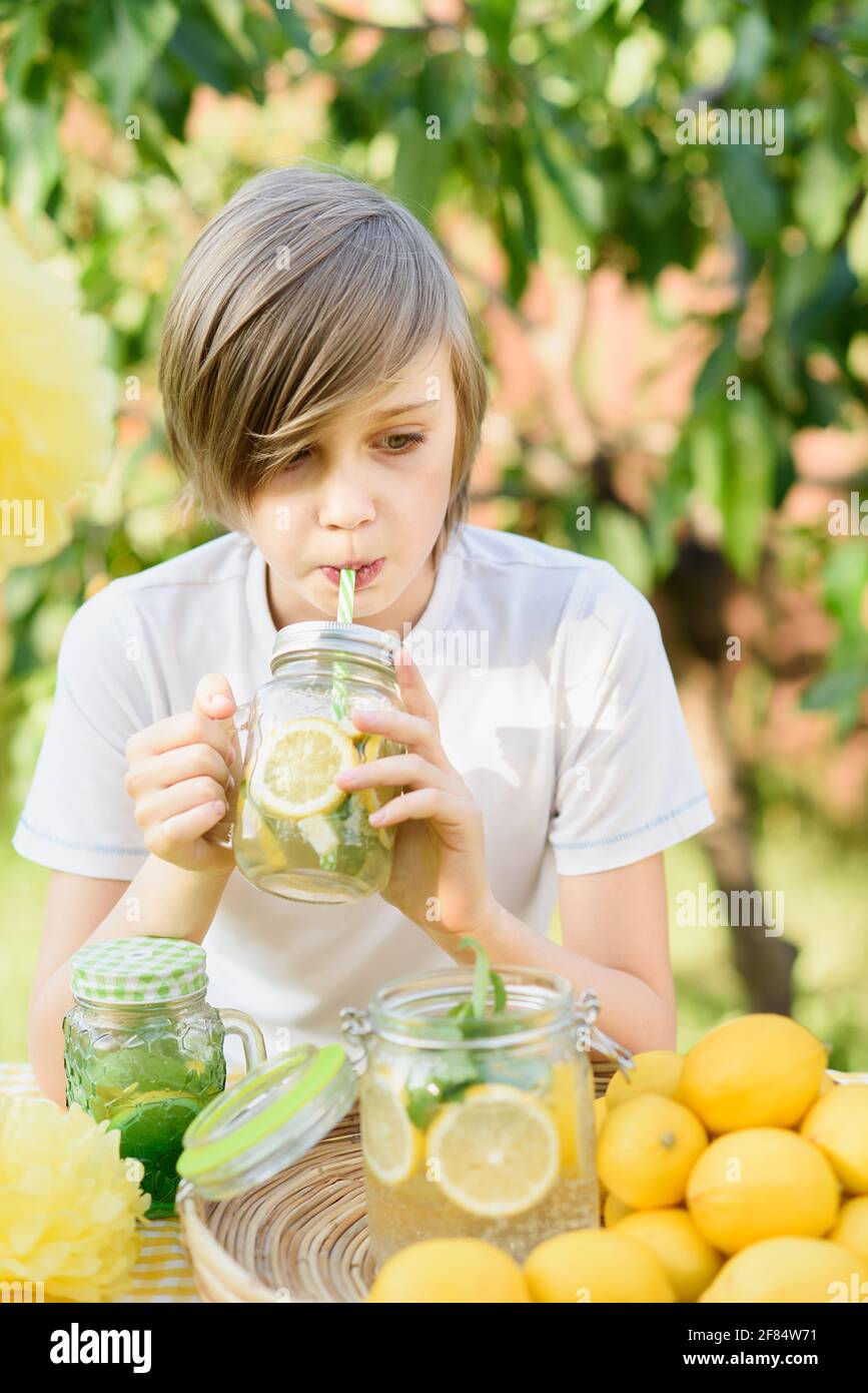 A 5-year old boy sits at a lemonade stand with cups and a pitcher of  lemonade Stock Photo - Alamy