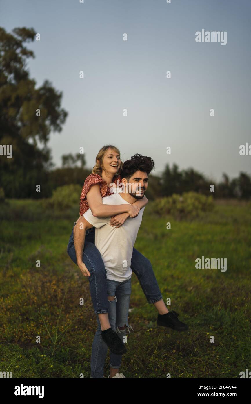 A vertical shot of a Spanish Caucasian couple in the park, him giving