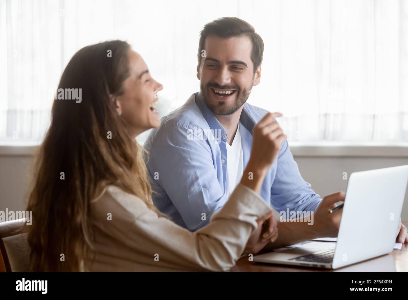 Happy millennial couple have fun using laptop at home Stock Photo
