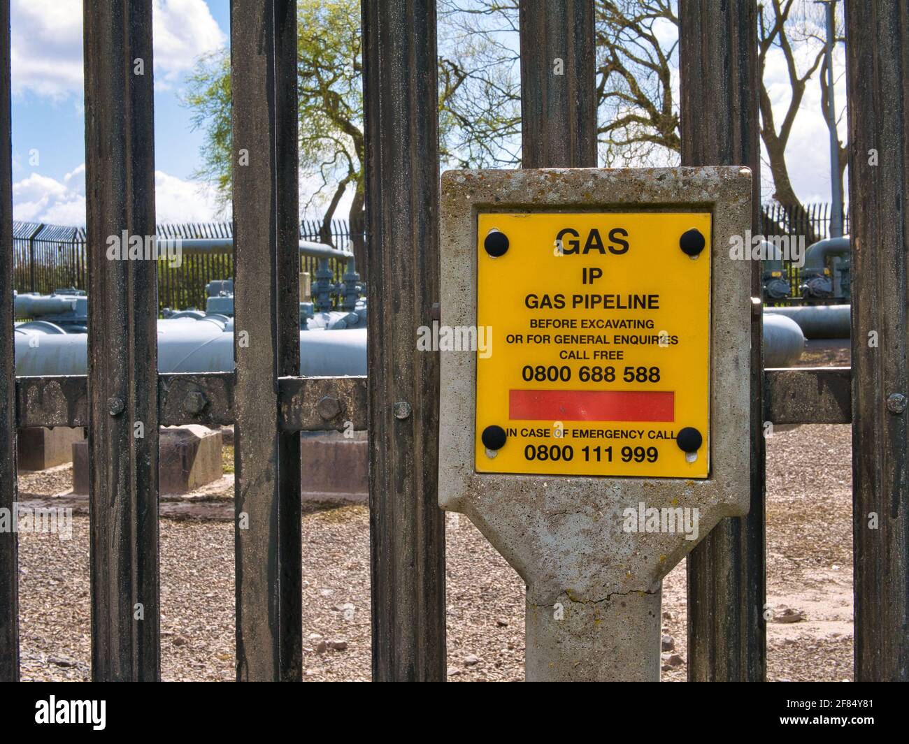 A yellow sign warning of an Intermediate Pressure (IP) gas pipeline at an Above Ground Installation (AGI) in the UK. Stock Photo