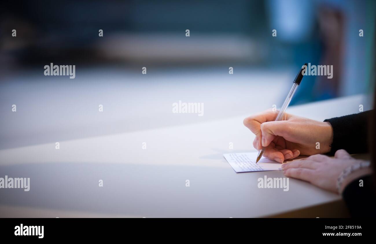 Close up view of womans hand writing in notebook. Girl making notes with pen on white table. Copy space Stock Photo