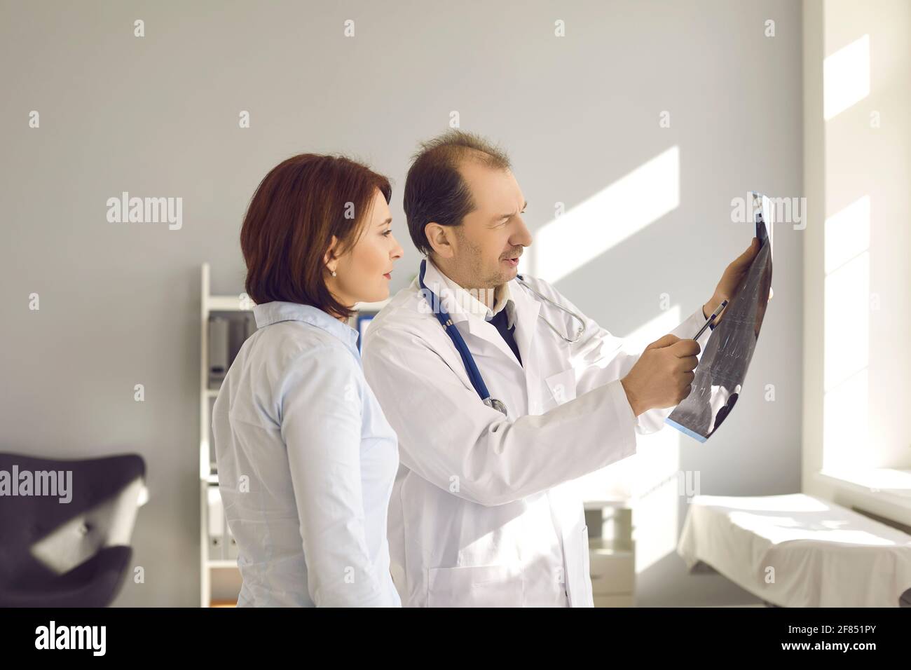 Doctor in the hospital office shows and explains to the patient an MRI scan or X-ray. Stock Photo
