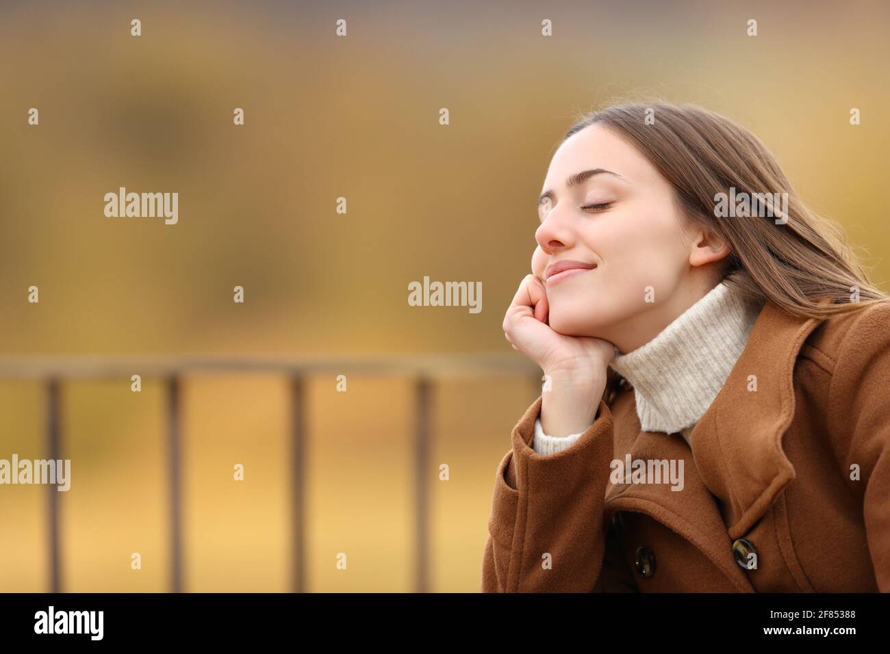 Happy woman relaxing with closed eyes sitting in a balcony in winter ...