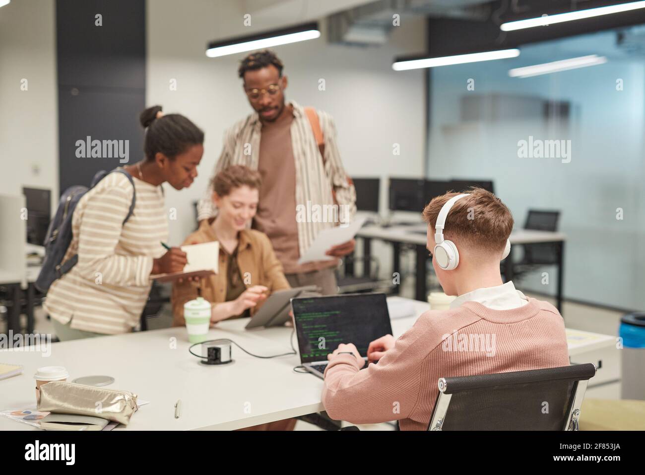 Group of young people using computers in school library, focus on young ...