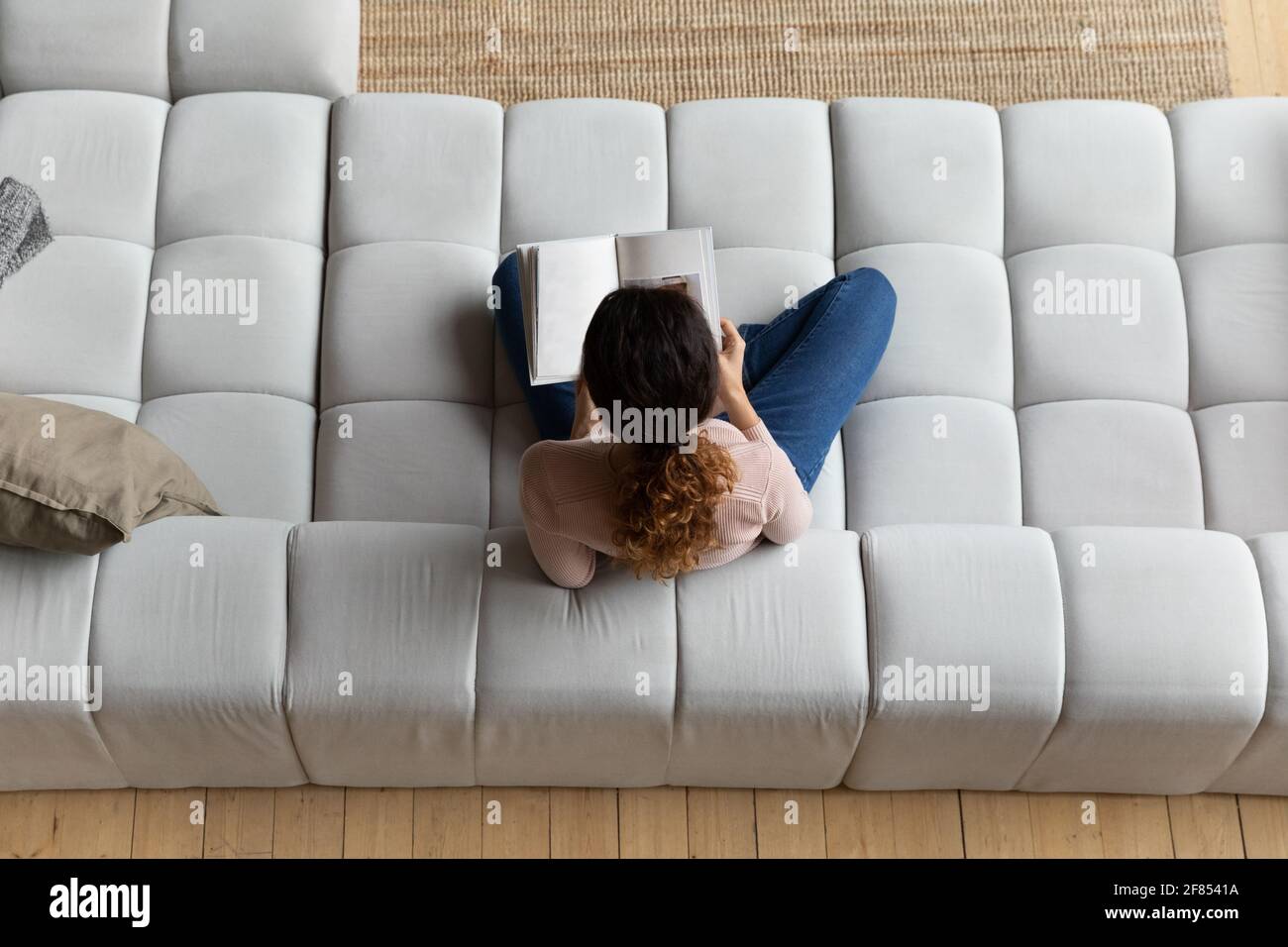 Young female sit on sofa read book with blank pages Stock Photo