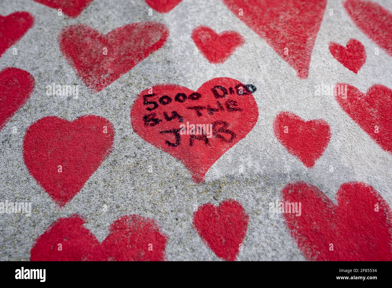 Anti-vaxxer graffiti appears on the wall. Coronavirus: National Covid Memorial Wall of Hearts, Westminster, London, UK. Stock Photo