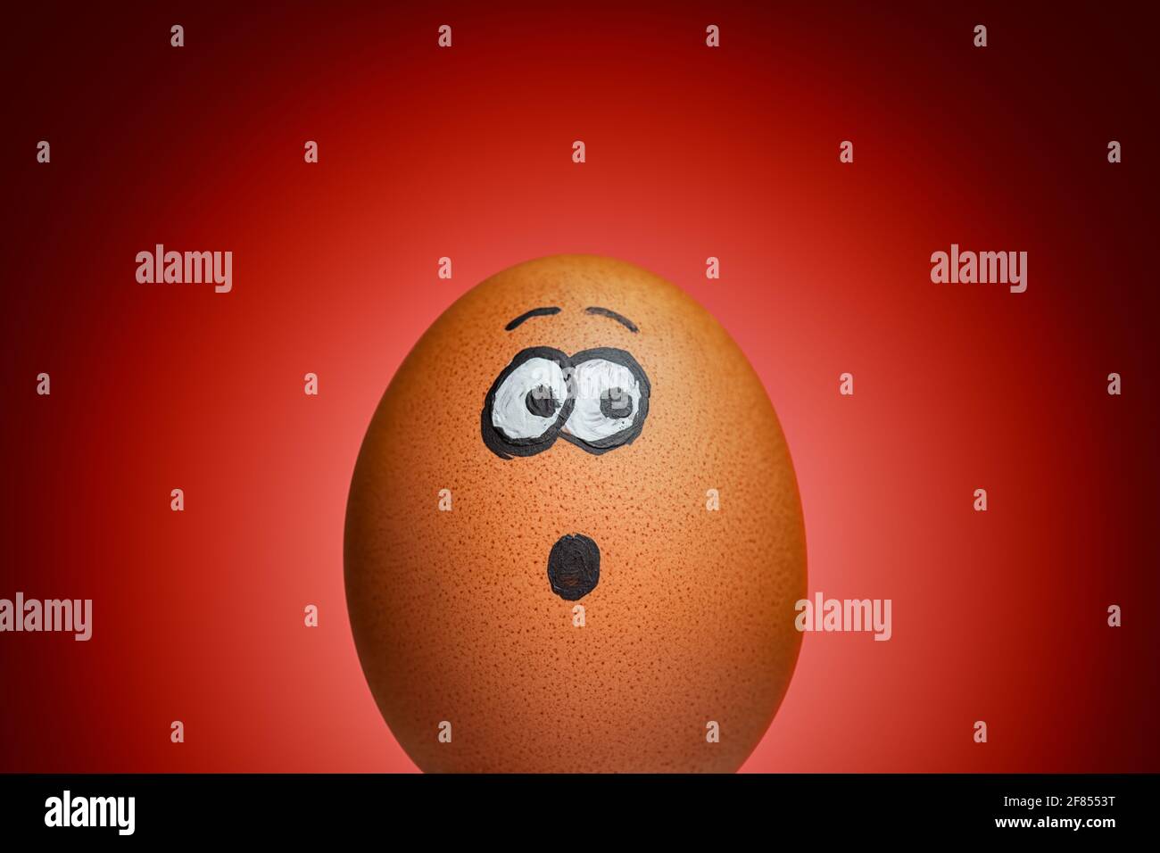 Scared or Surprised Egg on Dramatic Red Background Stock Photo