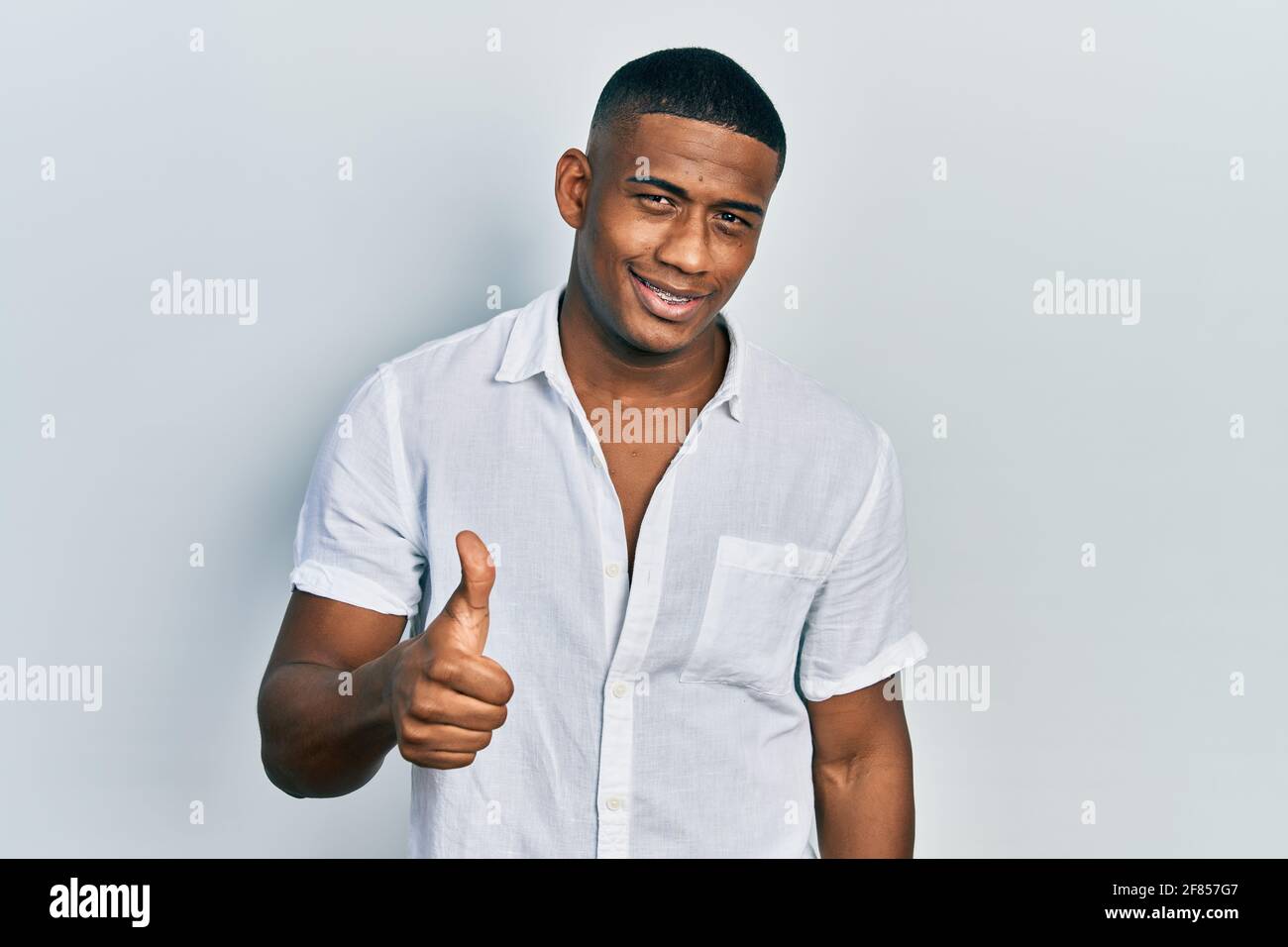 Young black man wearing casual white shirt doing happy thumbs up ...