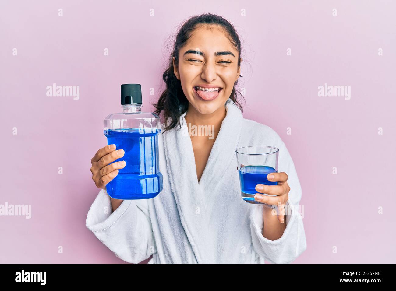 Hispanic teenager girl with dental braces holding mouthwash sticking