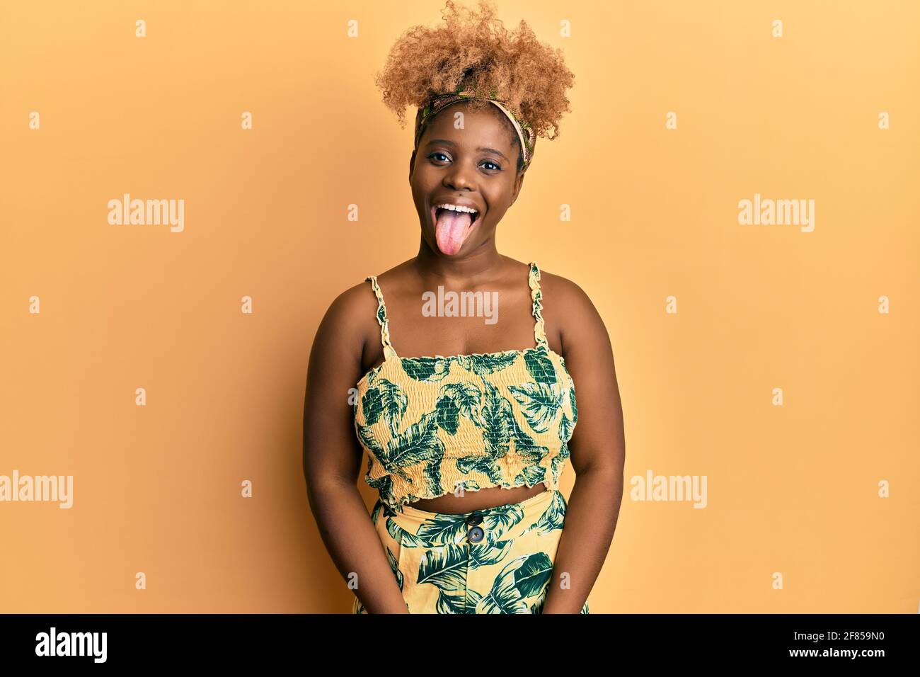 Young african woman with afro hair wearing summer dress sticking tongue ...