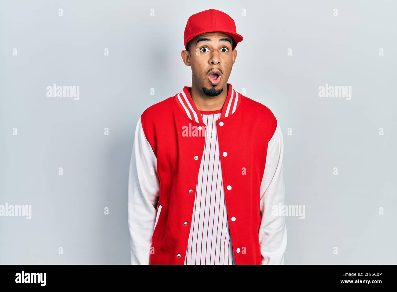 Young african american man wearing baseball uniform afraid and shocked ...