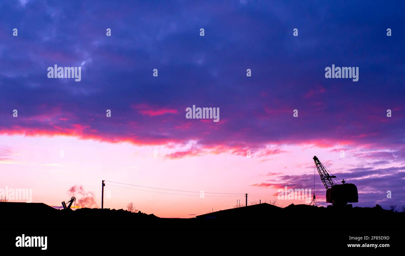 Escalator at sunset, industrial plant. Mining. Tractor digs earth Stock Photo