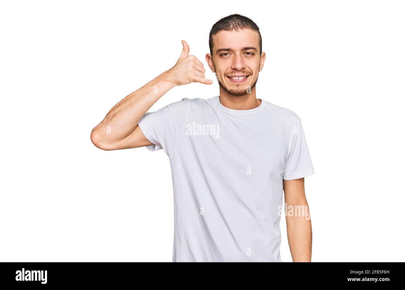 Hispanic young man wearing casual white t shirt smiling doing phone ...