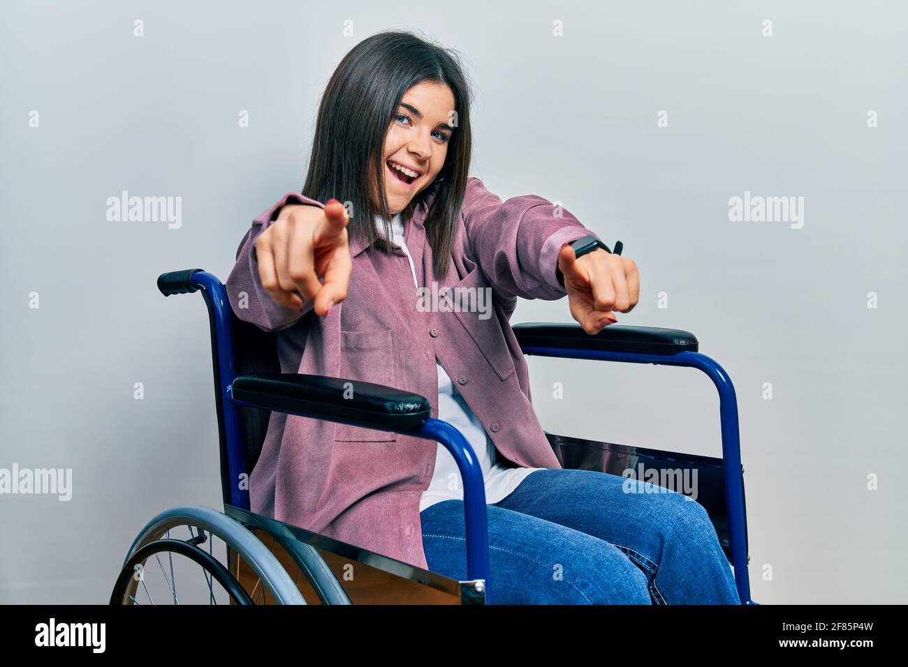 Young brunette woman sitting on wheelchair pointing to you and the ...