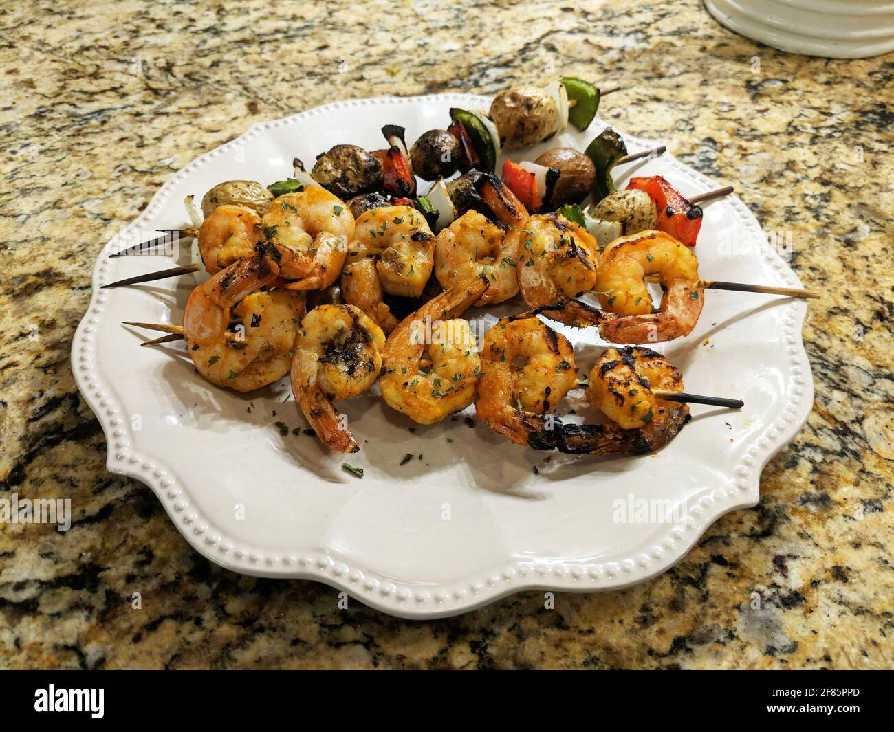 Grilled shrimp on skewers with vegetables on plate. Stock Photo