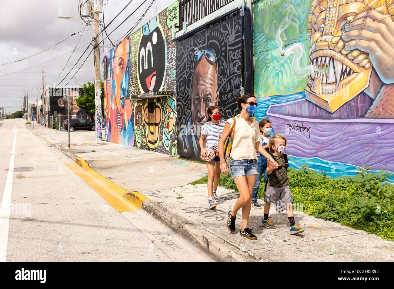 A young family walks by walls covered in graffiti art in the Wynwood Art District, Miami, FLorida, USA Stock Photo