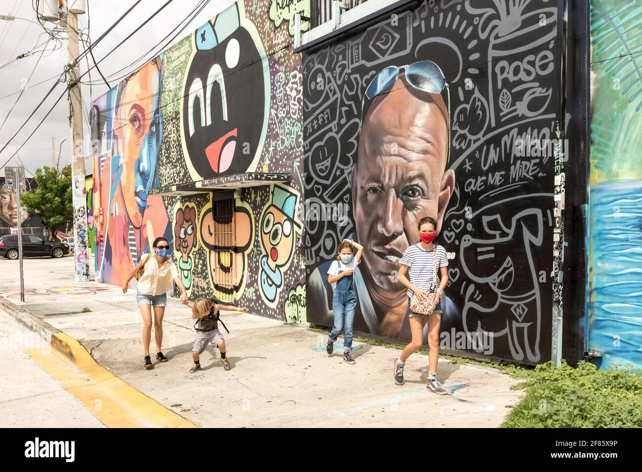 A sightseeing family walks by walls covered in graffiti art in the Wynwood Art District, Miami, FLorida, USA Stock Photo