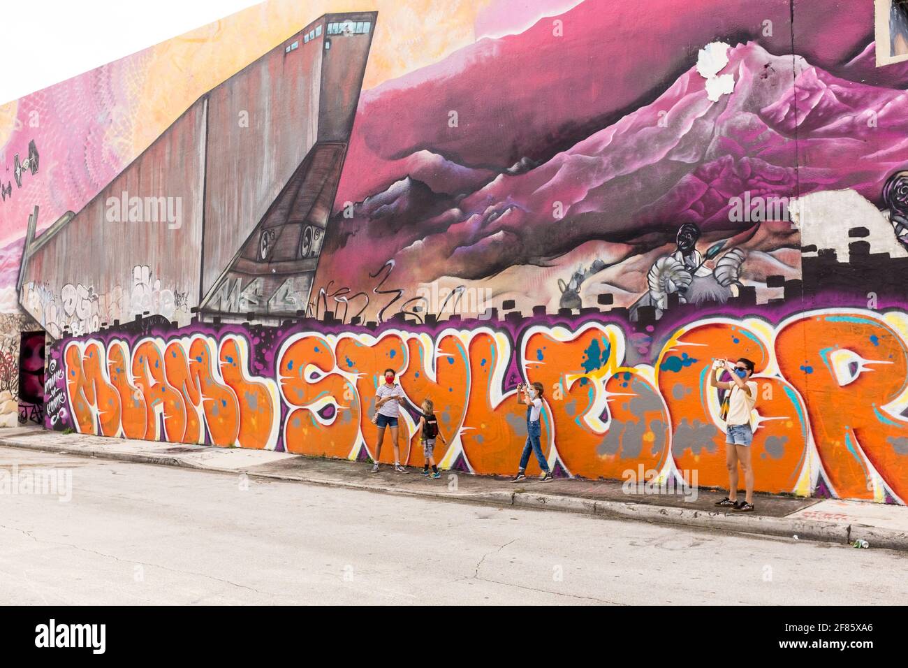 A family stands by a wall covered in graffiti art in the Wynwood Art District, Miami, FLorida, USA Stock Photo