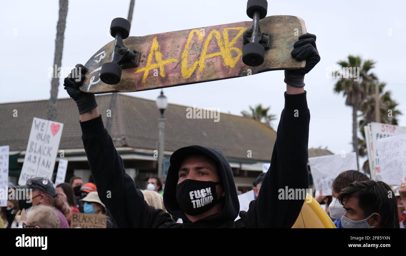 Huntington Beach, CA, USA. 11th Apr, 2021. A man holds a skateboard with an anti-police message towards police officers during a counter-protest against a 'White Lives Matter' rally on Huntington Beach Pier. Credit: Young G. Kim/Alamy Live News Stock Photo