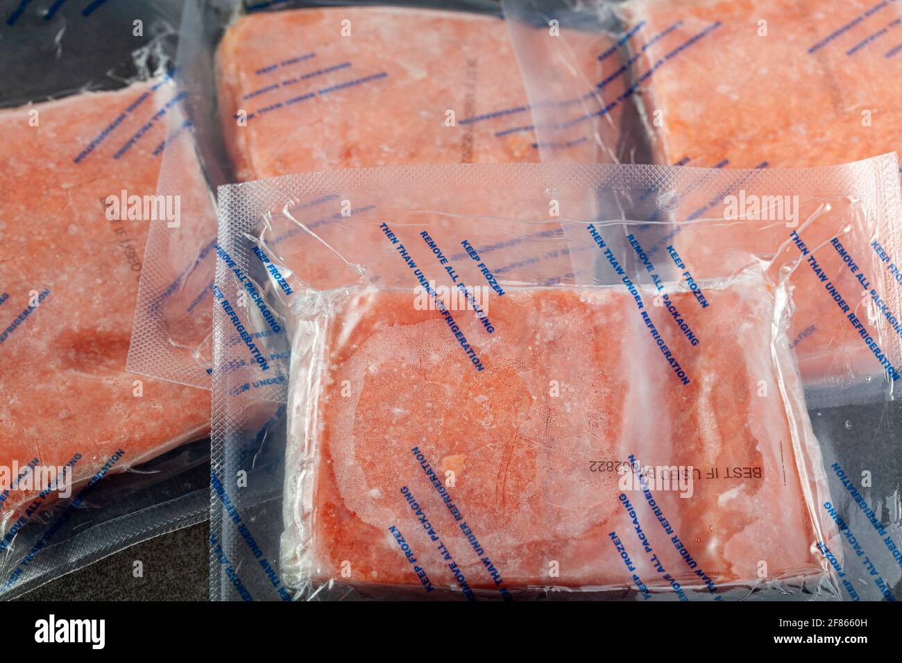 Closeup isolated image of four packs of individually packaged salmon fillets. The air tight vacuum sealed packs are frozen and the instructions say th Stock Photo