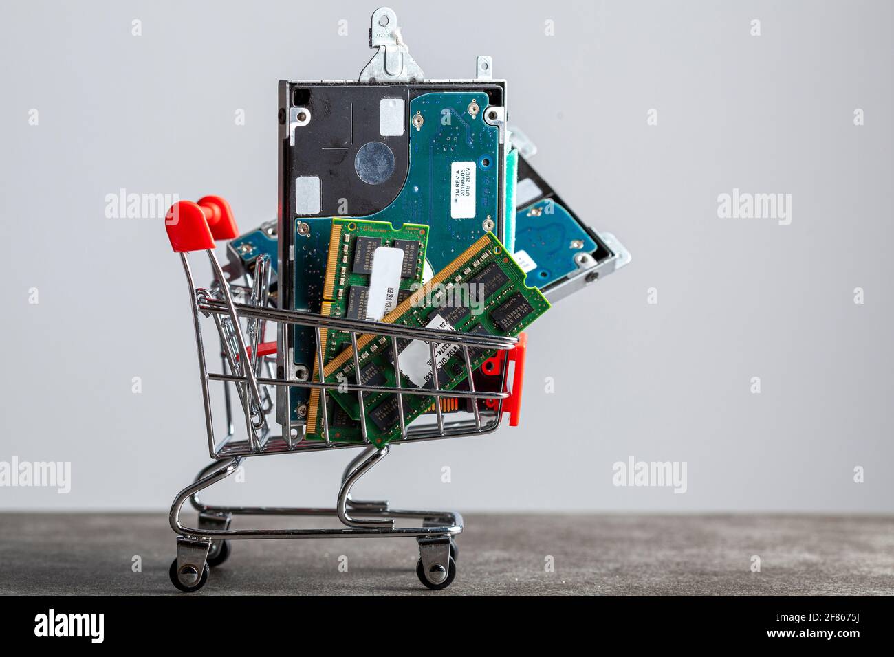A concept image with a small shopping cart filled with computer parts including RAM memory cards and a hard drive. Shopping for technology, consumer e Stock Photo