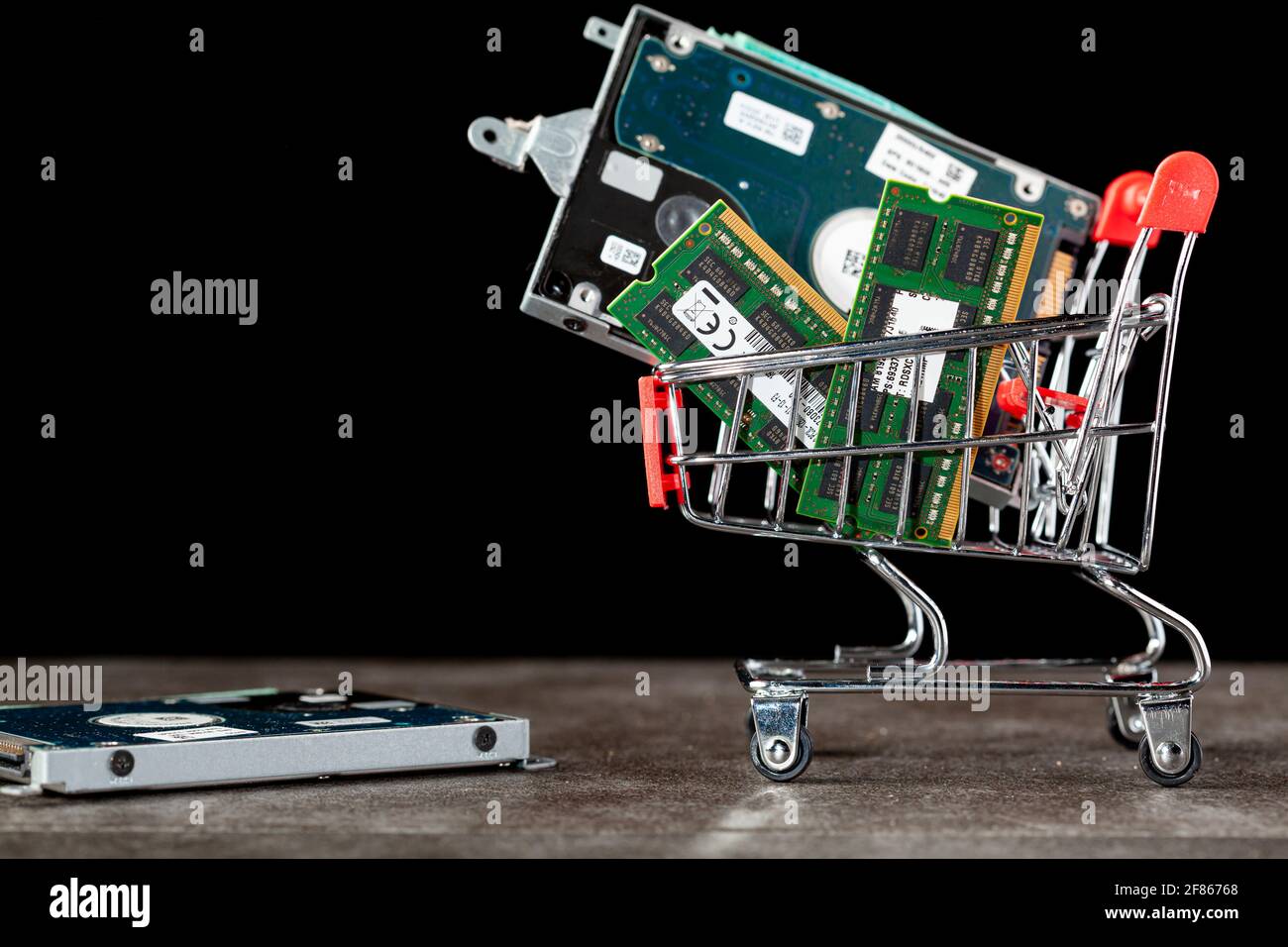 A concept image with a small shopping cart filled with computer parts including RAM memory cards and a hard drive. Shopping for technology, consumer e Stock Photo