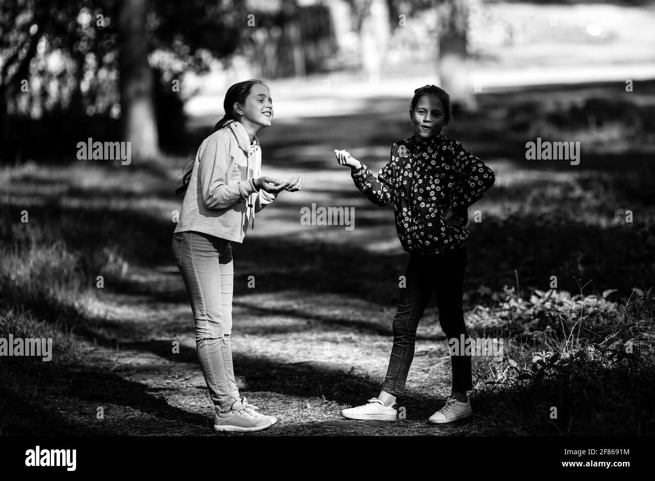 Two girls girlfriends are talking emotionally outdoors. Black and white photo. Stock Photo